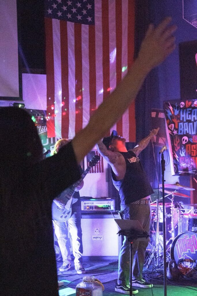 Hands raised in the crowd at a Laces Out show, American flag on the wall