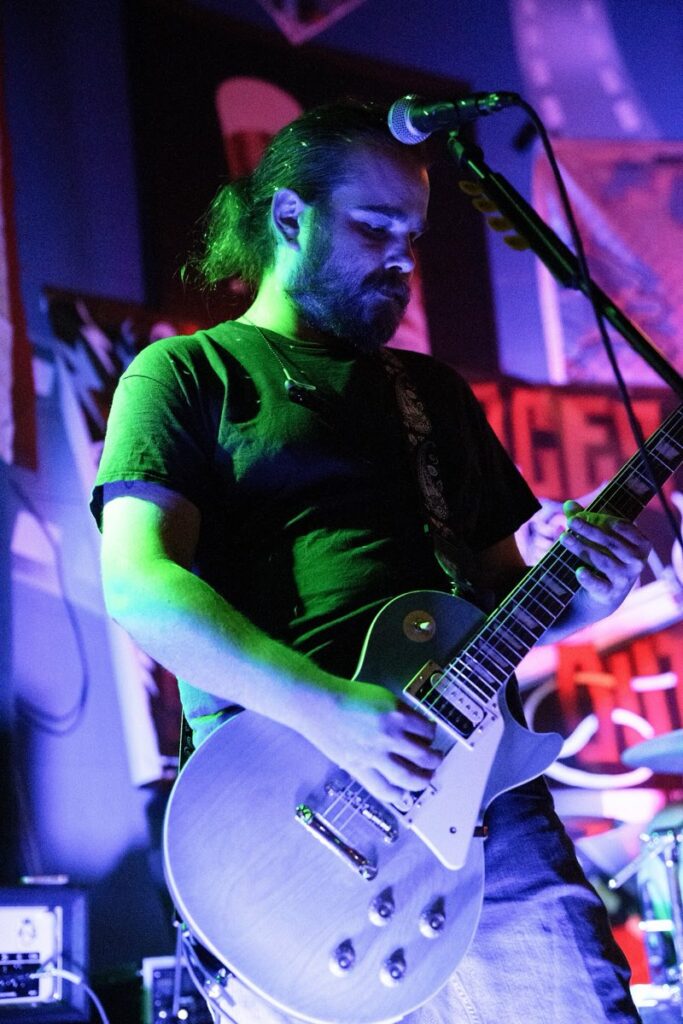 Laces Out guitarist playing a Les Paul under green stage light