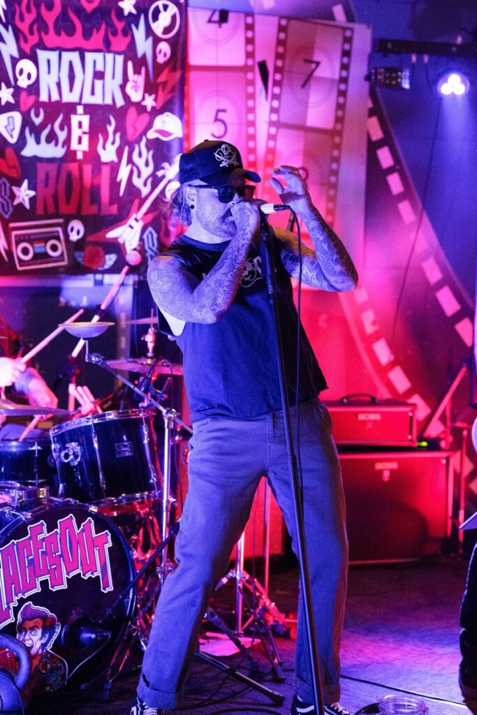 Laces Out singer gripping the microphone under pink and purple stage light