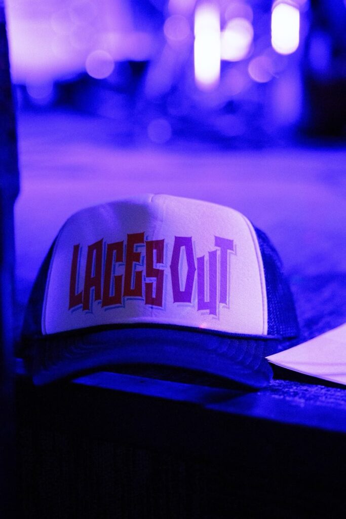 Laces Out trucker hat resting on a table in blue light